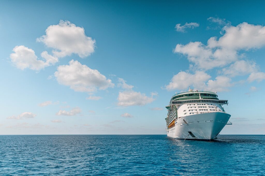 white and blue ship on sea under blue sky and white clouds during daytime